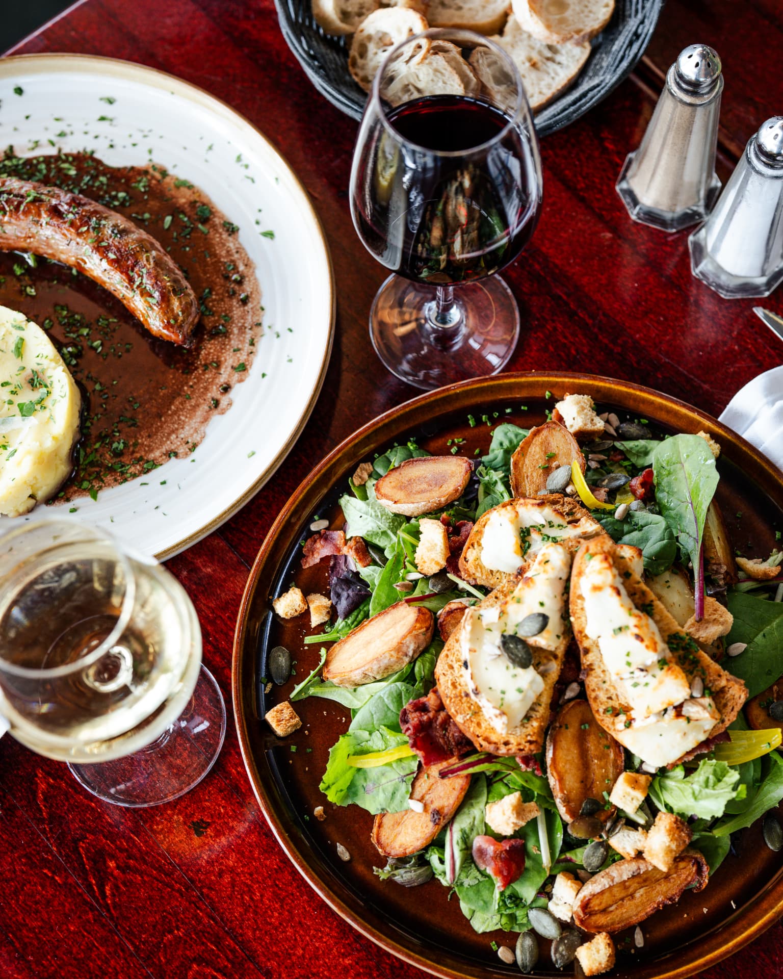 Salade de chèvre chaud et saucisse purée maison avec un verre de vin