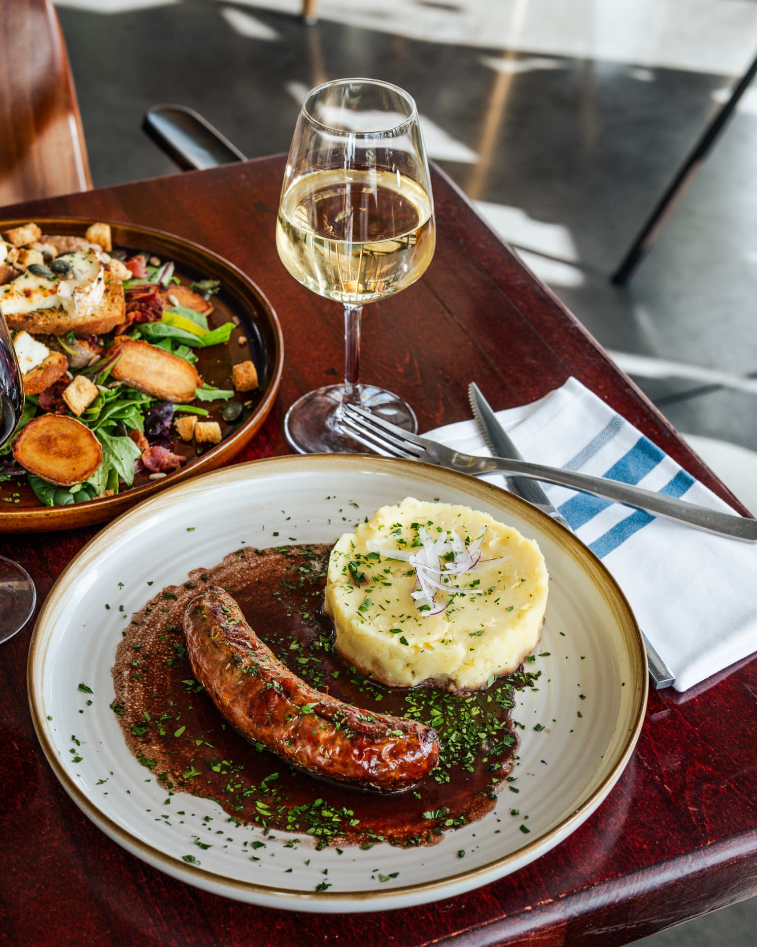 Saucisse grillée, purée maison et verre de vin blanc en terrasse