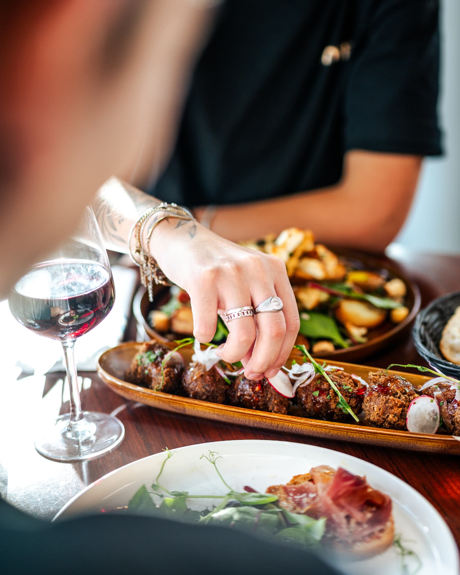 Convives se servant sur une planche à partager au Totem, verre de vin à la main